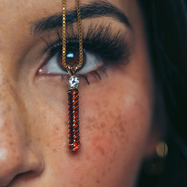 Close-up of a woman's face with a decorative gold and red pendant on her nose.