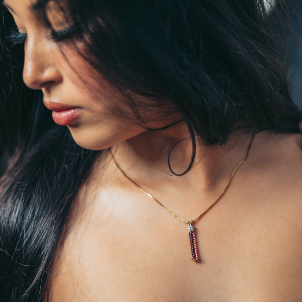 Woman wearing a necklace with a pendant, close-up of her neck and shoulder.