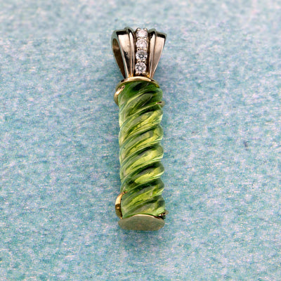 Green tourmaline with a silver and diamond pendant on a textured light blue background